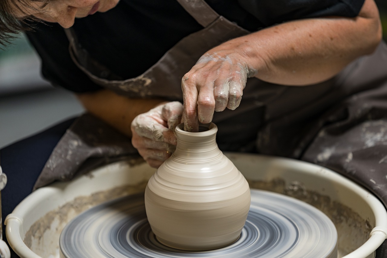 En person drejer en vase i ler